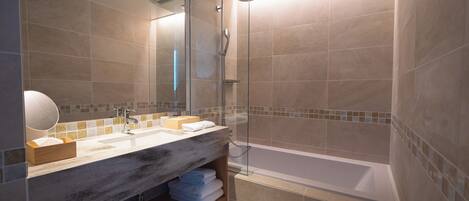 A modern bathroom with a large mirror, two sinks, a shower, and a bathtub.