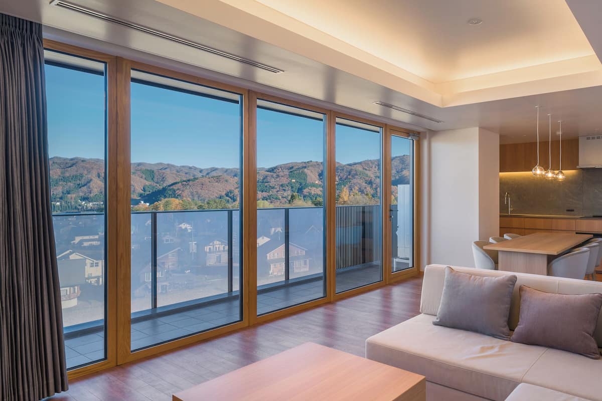 A modern living room with a large sliding glass door leading to a balcony with a city view.