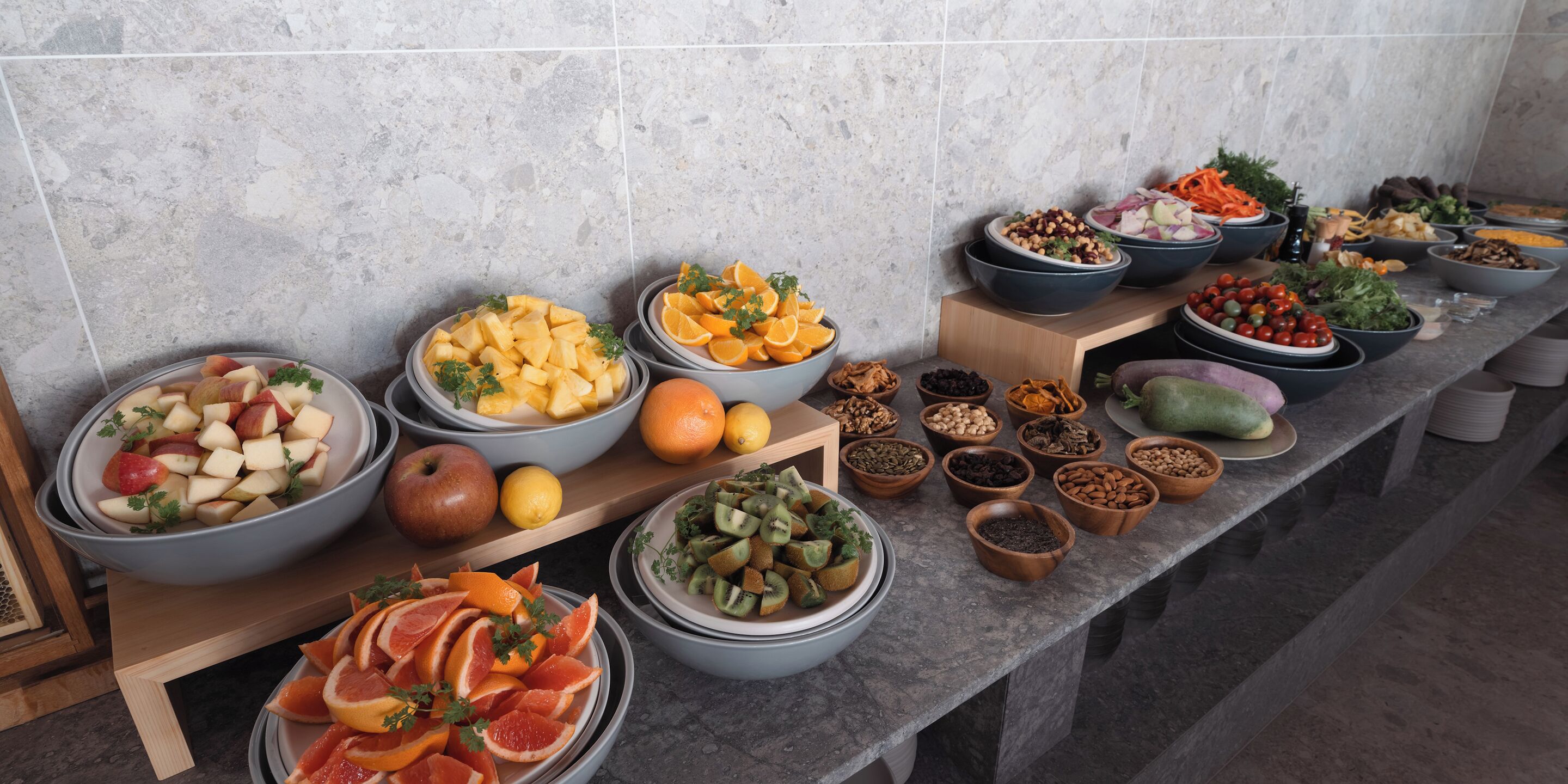 A buffet table with various fruits and nuts arranged in bowls.