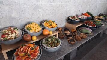 A buffet table with various fruits and nuts arranged in bowls.