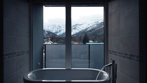 A bathroom with a bathtub and a view of snow-covered mountains through a large window. - HOTEL LA VIGNE HAKUBA by Onko Chishin (Hakuba)