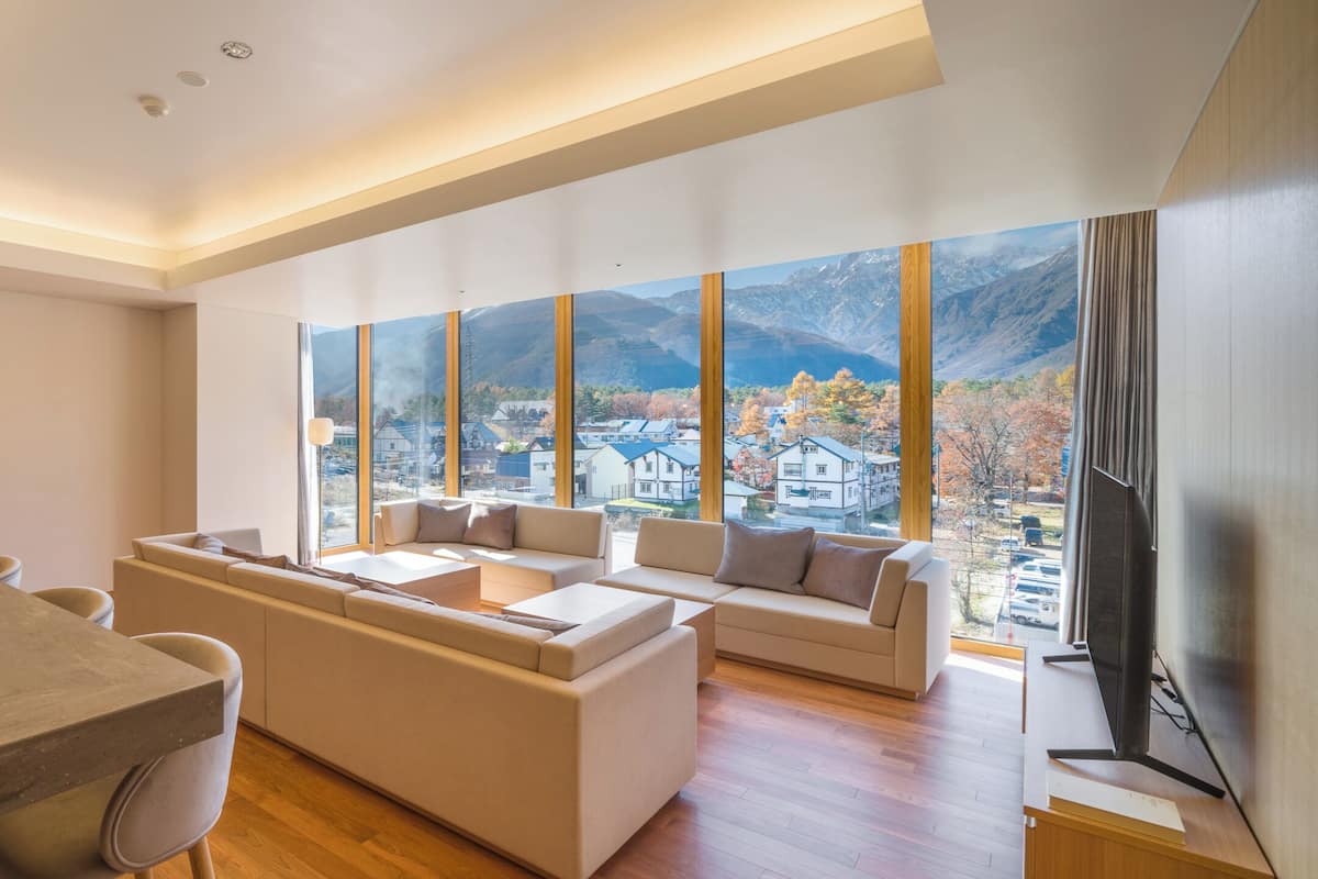 A modern living room with a large window, a dining area, and a flat-screen TV.