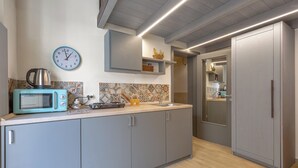 Uma cozinha moderna com armários cinzas, um micro-ondas, um relógio e uma pia.