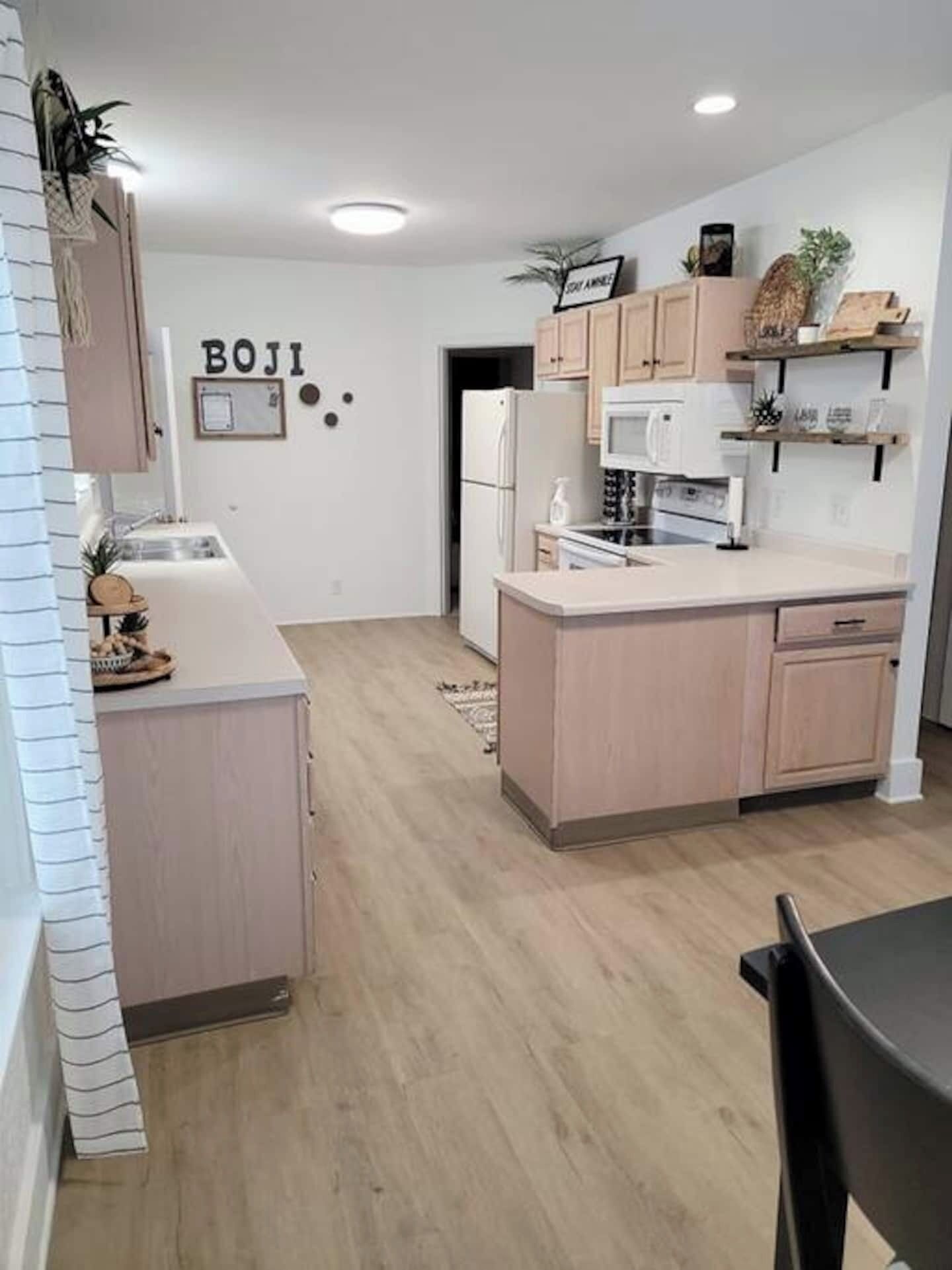 A modern kitchen with light wood cabinets, a central island, and a white countertop.