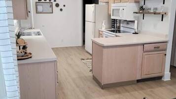 A modern kitchen with light wood cabinets, a central island, and a white countertop.
