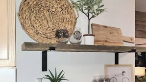 A kitchen shelf with a woven basket, a potted plant, and various glass containers.