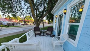 A porch with white railings, two wicker chairs, and a table.