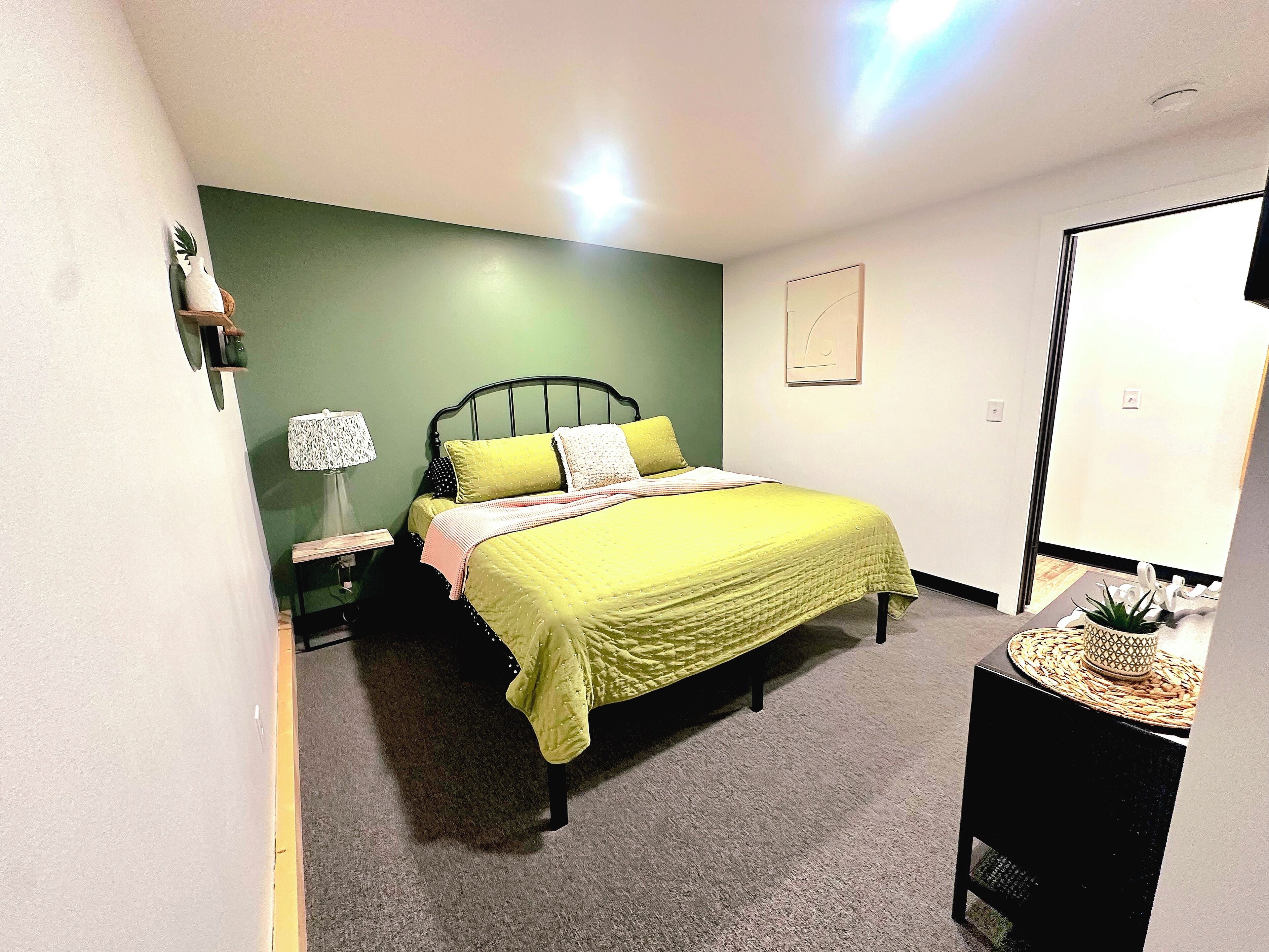 Une chambre à coucher avec un lit, une table de chevet, une lampe et une petite plante en pot.