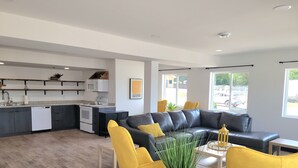 Ein modernes Wohnzimmer mit einem schwarzen Ledersofa, gelben Sesseln und einem Esstisch.