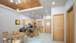 Una cocina moderna con armarios de madera, una zona de comedor con una mesa redonda y sillas, y una isla central.