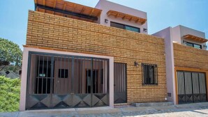 Un edificio moderno de dos pisos con fachada de ladrillo, ventanas amplias y entrada protegida por una reja.