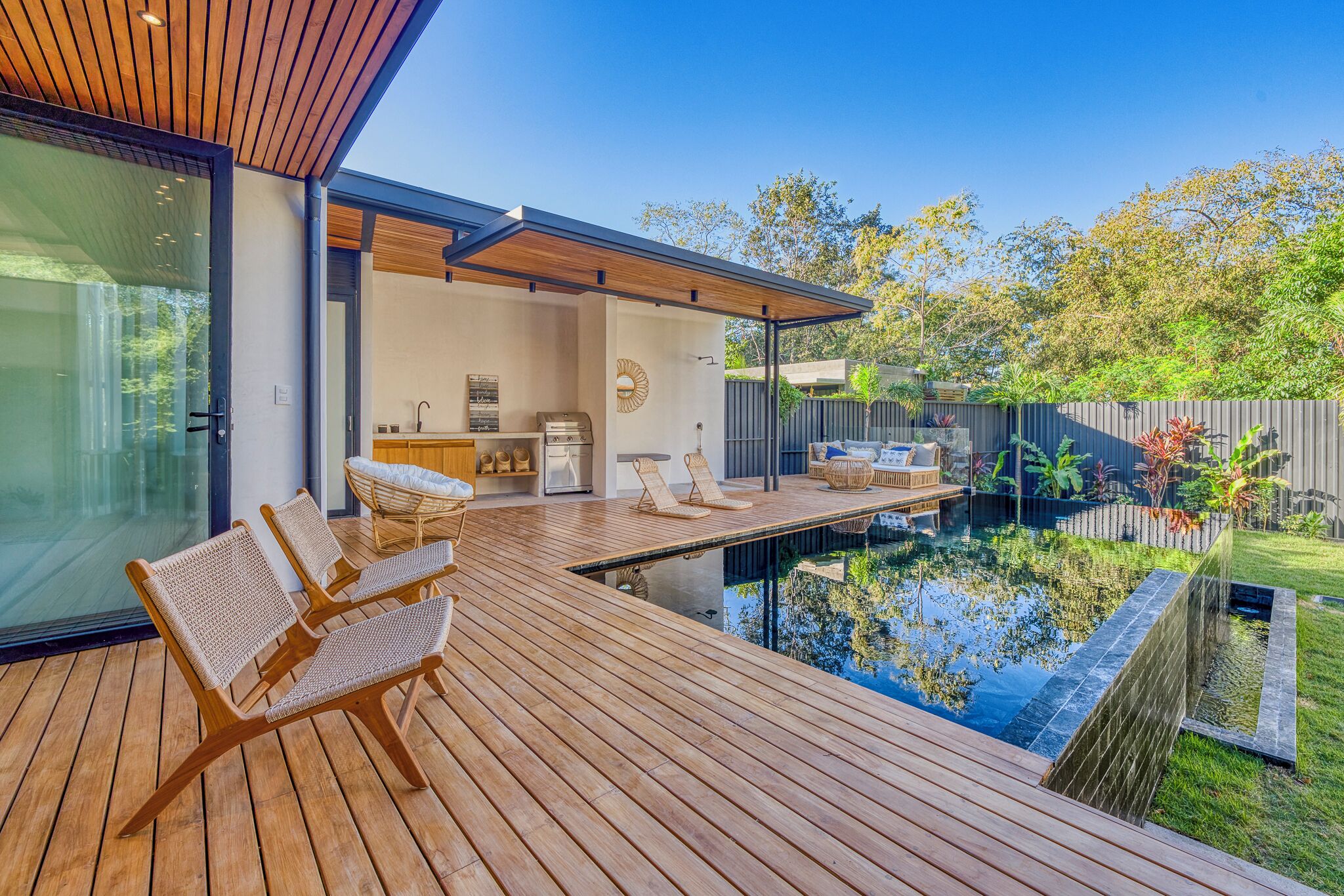 Outdoor spaces are perfectly designed to relax with a wood deck, infinity pool and green areas.