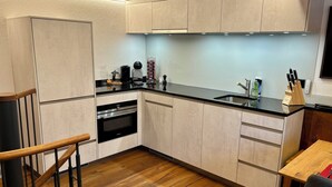 Una cocina moderna con armarios de colores claros, una encimera negra y un horno empotrado.