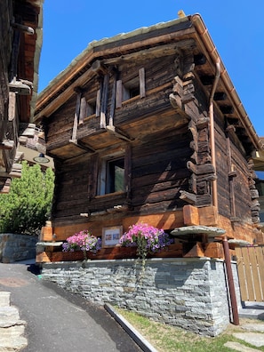 A log cabin with a stone foundation, wooden balcony, and flower boxes.
