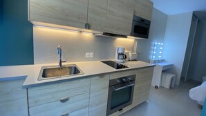 A modern kitchen with a stainless steel sink, a built-in oven, and a microwave. - Cozy apartment with private garden near thermal baths (Balaruc-les-Bains)