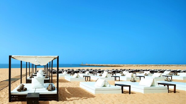 A beachside lounge area with white lounge chairs and a canopy structure. - Lótus by Check-in Portugal (Quarteira)