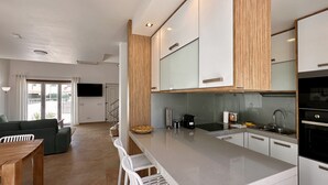 A modern kitchen with a central island, built-in appliances, and a dining area with a table and chairs. - Lótus by Check-in Portugal (Quarteira)