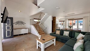 A modern living room with a staircase, a sofa, a coffee table, and a TV. - Lótus by Check-in Portugal (Quarteira)