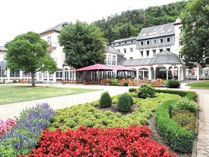 Un hôtel doté d’un patio avec jardin, d’un espace extérieur aménagé pour s’asseoir et d’un grand bâtiment avec de nombreuses fenêtres et une partie couverte.