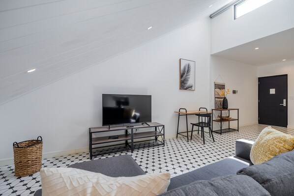A modern living room with a flat-screen TV, a sofa, a coffee table, and a patterned floor. - w* | Sunny Loft in Plaza Catedral (Panamá)