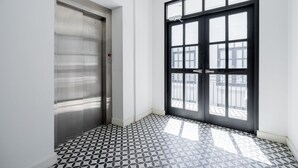 Un couloir avec un sol à motifs, une porte et une fenêtre donnant sur l’extérieur.