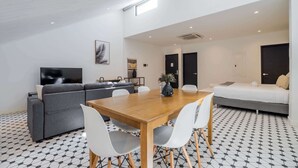 Un salon moderne avec un canapé, une table à manger et des chaises, un téléviseur à écran plat et un sol à motifs.