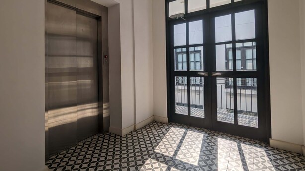 A room with a tiled floor, a door, and a window with a view of a balcony. - w* | Chic Loft in Plaza Catedral (Panamá)