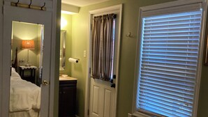 A bedroom with a bed, a dresser, a mirror, and a window with blinds.