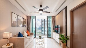 A modern living room with a sofa, a coffee table, a TV, and a ceiling fan. - Landmark 81 Luxury - SaigonHomes (Ho Chi Minh City)