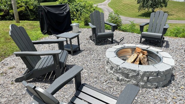 A fire pit surrounded by Adirondack chairs and a table, set on a gravel area with a view of a road and greenery. - Great vacation home for your next adventure. Located in Andrew’s North Carolina. (Andrews)