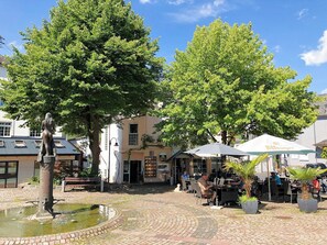 Ein Innenhof mit Brunnen, Sitzgelegenheiten und einem Essbereich im Freien unter Sonnenschirmen.