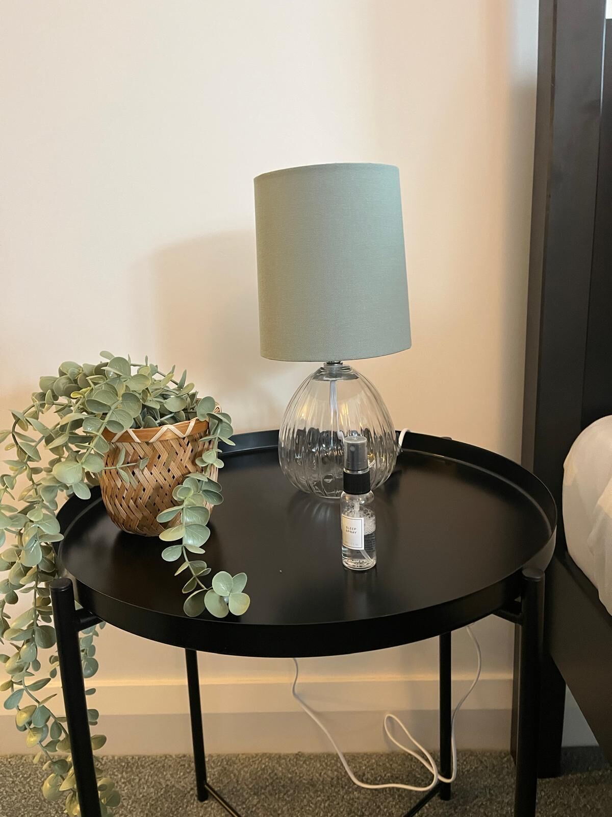 Une petite table ronde avec une lampe et un panier décoratif.