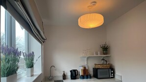 A compact kitchen with a window, a sink, a microwave, and a hanging light fixture. - The Briarcroft Wayth Hotels (Goole)