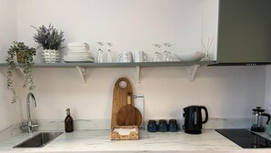 A modern kitchen with a marble countertop, a wooden cutting board, a coffee maker, and jars on the shelf. - The Briarcroft Wayth Hotels (Goole)