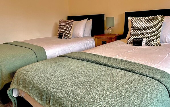 A hotel room with two single beds, each with a pillow and a bedside table with a lamp. - The Briarcroft Wayth Hotels (Goole)