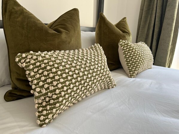 A bed with two large pillows and a smaller one, all in a solid color.