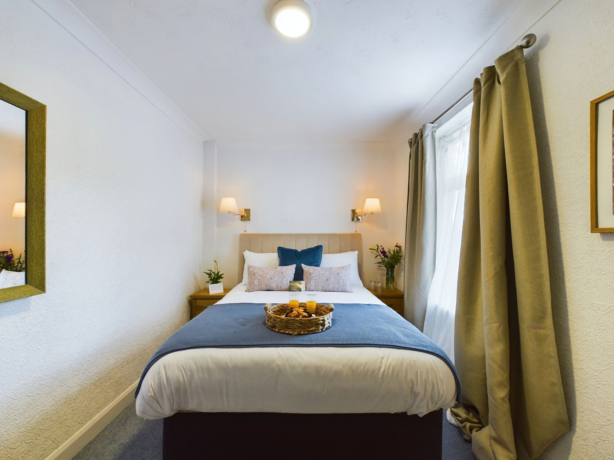 Habitación de hotel ordenada con cama, mesitas de noche, lámparas y una ventana con cortinas.