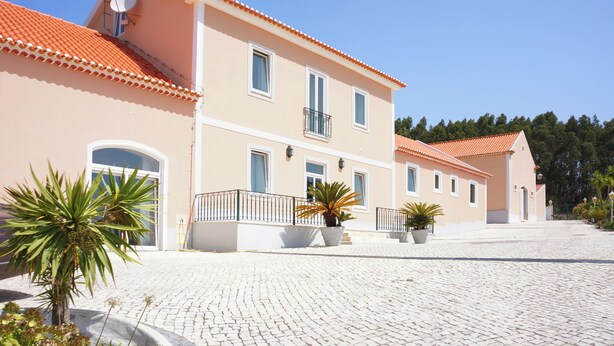 A two-story building with a tiled roof, a paved courtyard, and potted plants. - Quinta da Carlota (Torres Vedras)