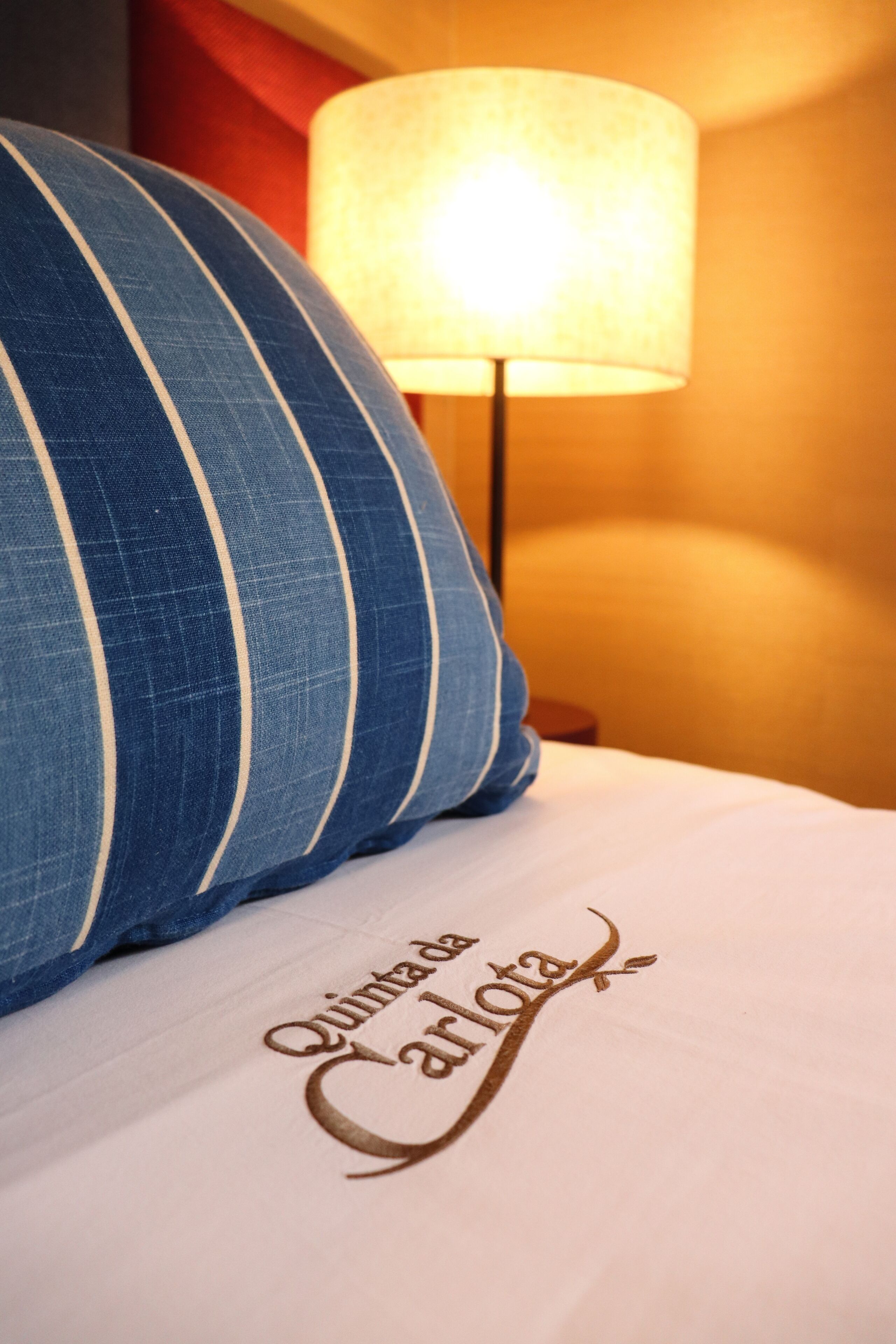 Una cama con un almohadón y una manta con bordado.