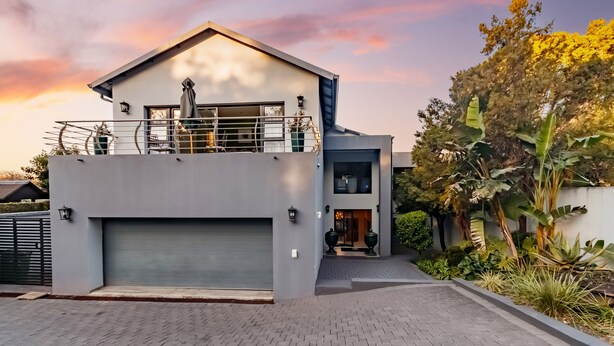 Une maison moderne à deux étages, dotée d’un garage, d’un balcon et d’un jardin bien entretenu.