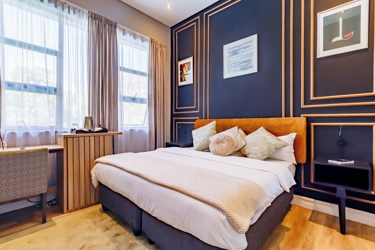 Een moderne slaapkamer met een groot bed, een bureau en een raam met gordijnen.