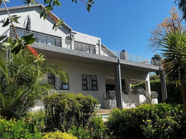 Enjoy the serene views from the upper floor balcony with a staircase leading down to the lush surroundings.