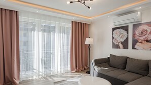 A modern living room with a grey sofa, a white ottoman, and a floor lamp. - Holiday Apartment Wasserfall in Holiday Home Bad Bertrich (Bad Bertrich)