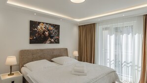 A hotel room with a large bed, a nightstand, a lamp, a painting on the wall, and a window with curtains. - Holiday Apartment Wasserfall in Holiday Home Bad Bertrich (Bad Bertrich)