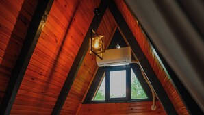 A cozy attic bedroom with a wooden sloped ceiling, a large bed with pillows, and a hanging light fixture. - Sapanca Pine Life (Sapanca)