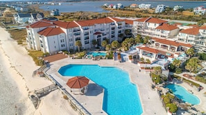 A resort with multiple buildings, a large central pool, and a beach area. - Villa Capriani 102B - Oceanfront - Pools - Restaurant - Premiere (North Topsail Beach)
