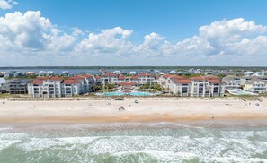Un hôtel en bord de mer composé de plusieurs bâtiments, doté d’une plage de sable et offrant une vue sur l’océan.