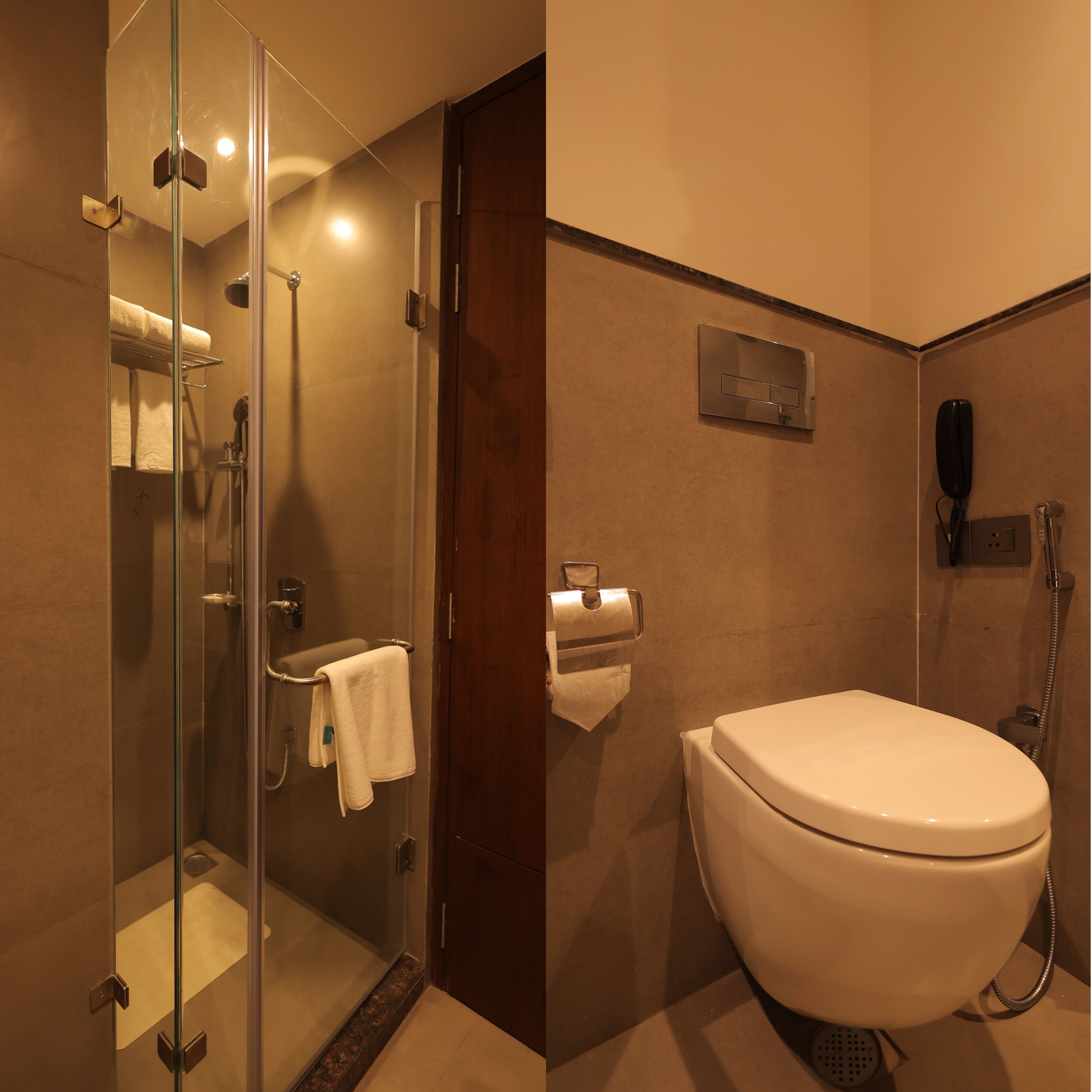 Un baño moderno con cabina de ducha de vidrio, inodoro y teléfono instalado en la pared.