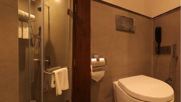Un baño moderno con cabina de ducha de vidrio, inodoro y teléfono instalado en la pared.