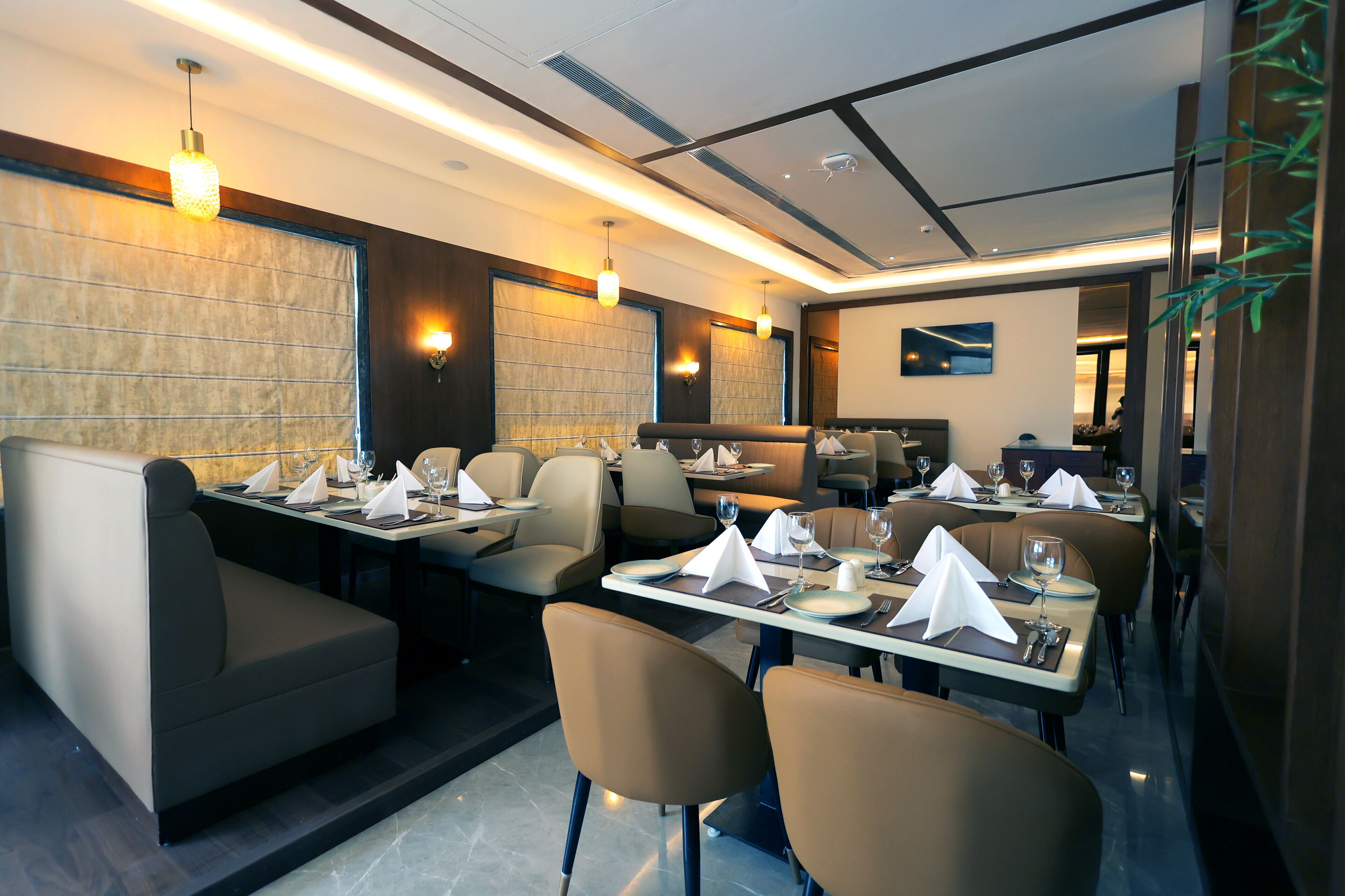 Un restaurante moderno con asientos tipo cabina y mesas, iluminación ambiental y un diseño limpio y contemporáneo.